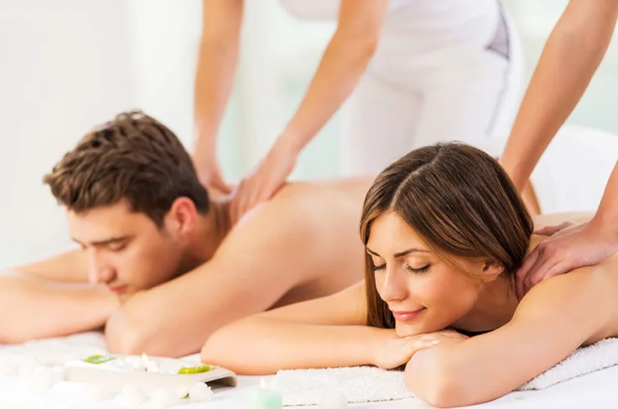 Couple receiving side-by-side massages from two therapists